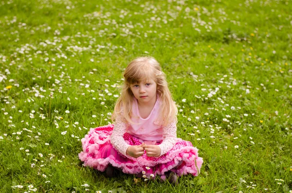Menina loira sentada no prado — Fotografia de Stock
