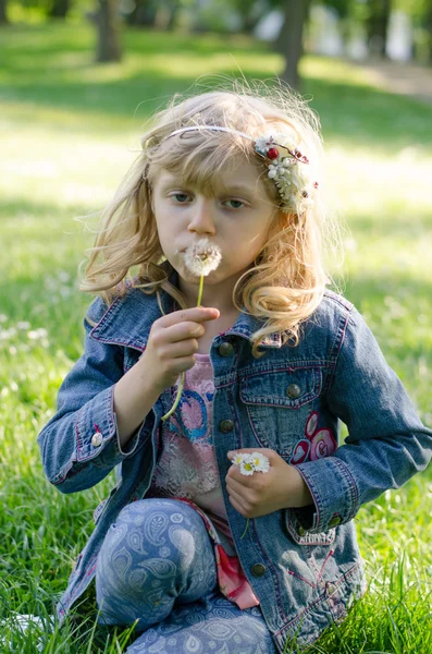 Blond girl blowing dandelion — Stock Photo, Image