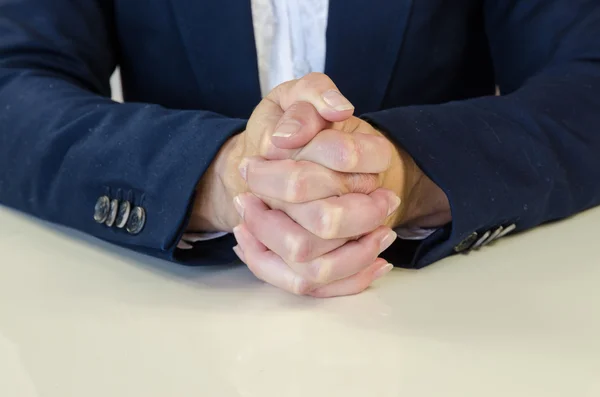 Clenched hands over desk — Stock Photo, Image