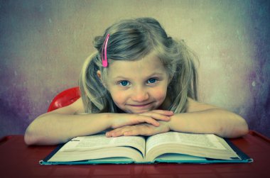 smiling blond little girl with open book