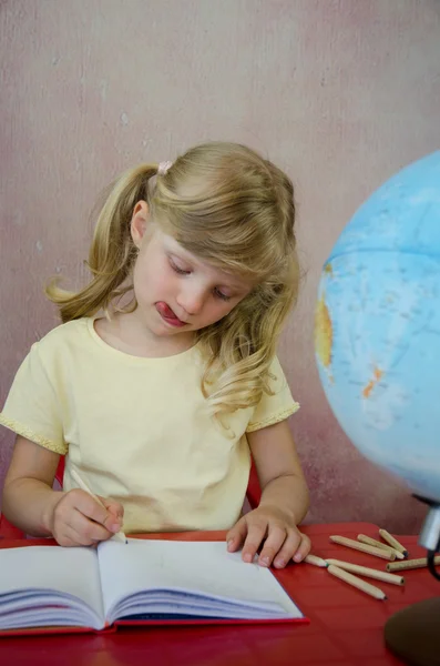 Concentrated little girl, notepad and globe — Stock Photo, Image