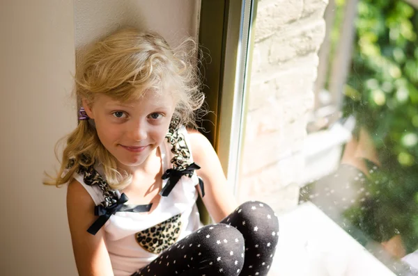 Chica con el pelo largo y rubio sentado en la mesa de la ventana —  Fotos de Stock