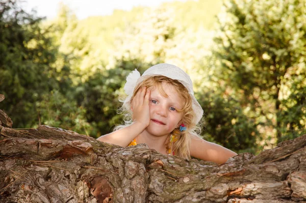 Lilla flickan bakom träd bålen porträtt — Stockfoto
