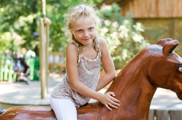 Girl in wooden horse — Stock Photo, Image