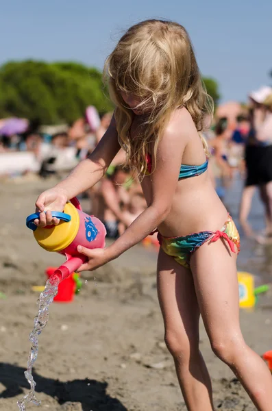 Barn hälla vatten på stranden — Stockfoto