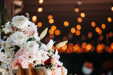 Koyu arka planda beyaz ve pembe güller. Sarı ve turuncu bokeh ışıkları var. Kopyalama alanı olan tatil arkaplanı.