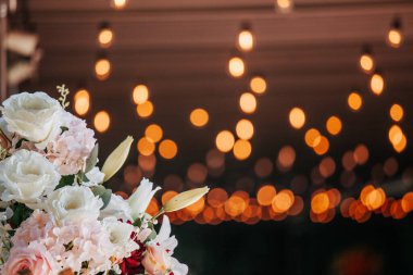 Koyu arka planda beyaz ve pembe güller. Sarı ve turuncu bokeh ışıkları var. Kopyalama alanı olan tatil arkaplanı.