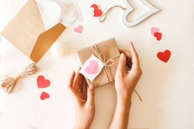 Sevgililer Günü hediyelerini jüt ip ve kağıt kalplerle kahverengi kağıda saran bir kadın..