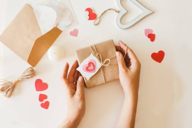 Sevgililer Günü hediyelerini jüt ip ve kağıt kalplerle kahverengi kağıda saran bir kadın..