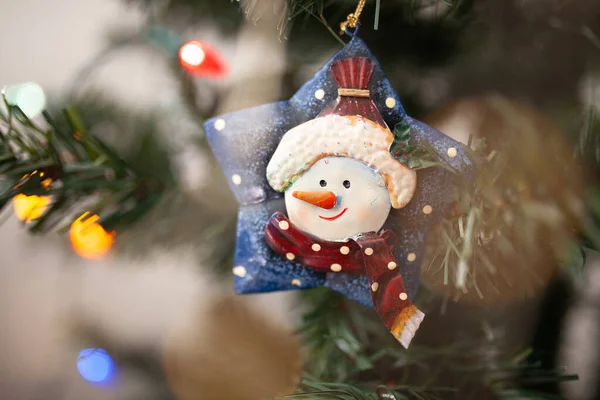 Kardan adam Noel ağacı süsü yeşil dalda ip ışıkları ve kopyalama alanı. Kış tatili geçmişi.