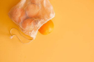 Meyve ve sebzeler için yeniden kullanılabilir plastik poşet. Portakal, turuncu arka planda, fotokopi alanı olan el yapımı tekstil poşeti. Sıfır atık