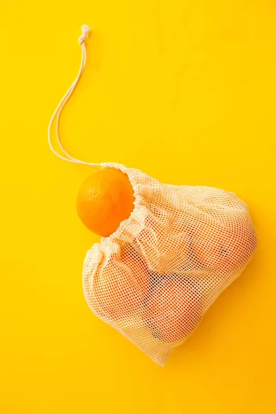 Meyve ve sebzeler için yeniden kullanılabilir plastik poşet. Portakal, turuncu arka planda, fotokopi alanı olan el yapımı tekstil poşeti. Sıfır atık