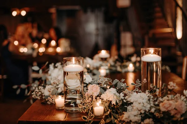 Güzel, lüks bir köy düğün masası dekoru. Cam kavanozlu, mumlu ahşap masalar. Beyaz güller ve oktavlar. Lüks çatı katı düğünü..