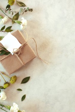 Bahar tatili çiçekleri - kahverengi kağıtlı beyaz arka plan hediye paketi, yeşil kasımpatı, beyaz karanfiller ve okaliptüs yaprakları.