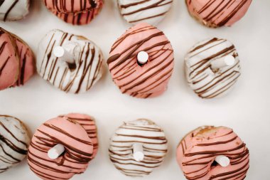 Beyaz duvar tezgahında beyaz ve pembe jöleli çörekler. Taze beyaz ve pembe çöreklerle beyaz ekran.