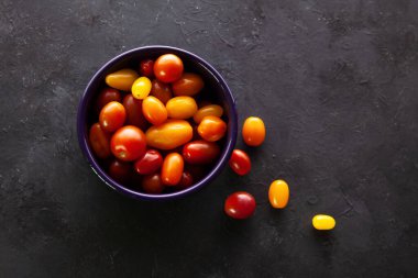 Koyu gri arka planda kiraz domatesli kase ve ahşap kutu.