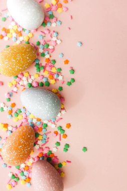 Pembe arka planda beyaz, gri ve sarı yumurtalar. Renkli serpiştirilmiş. Paskalya tatili.