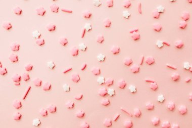 Açık pembe arka planda pembe ve beyaz yıldız şekilli serpinti. Pembe arka planda renkli yenilebilir pasta süslemesi.