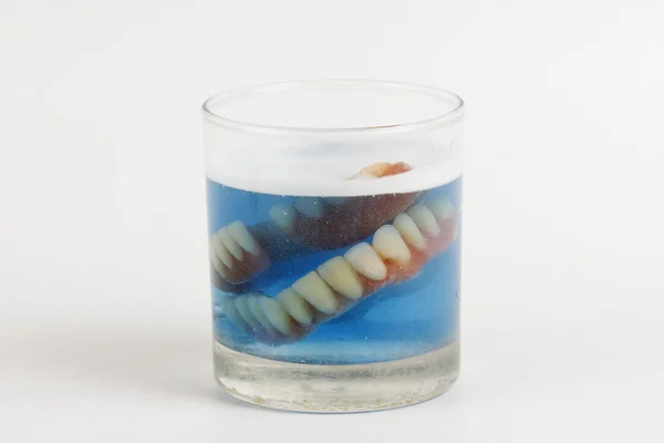 Dentiera in un bicchiere con pastiglie per la pulizia — Foto Stock