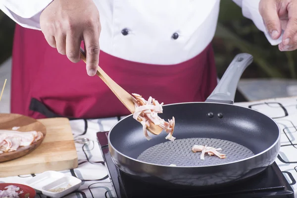 Chef colocando bacon na panela para frito — Fotografia de Stock