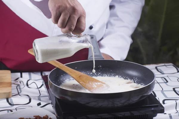 Chef pouring fresh milk to the pan — Stock Photo, Image
