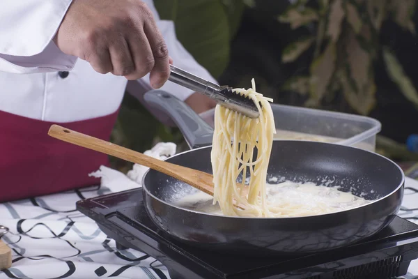 Spaghetti mit der Zange auf die Pfanne heben — Stockfoto