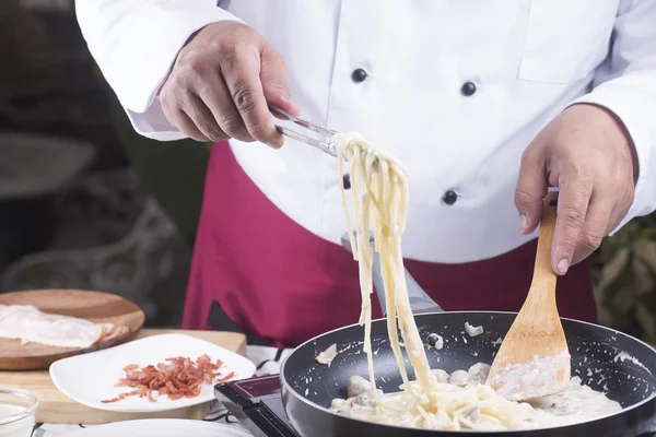 Spaghetti lifted from the pan with tongs — Stock Photo, Image