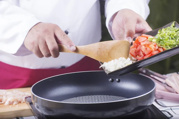 Koch kocht Zwiebeln, Tomaten und grüne Paprika — Stockfoto