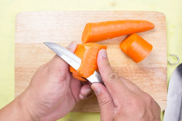 Koki mengupas wortel di papan kayu — Stok Foto