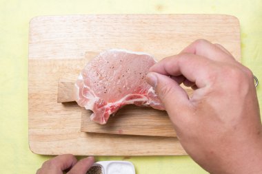 Şef için ham porkchop biber koyarak 