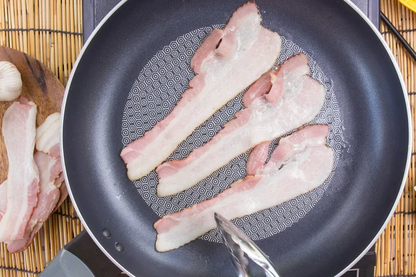 Chef frying bacon in the pan — Stock Photo, Image