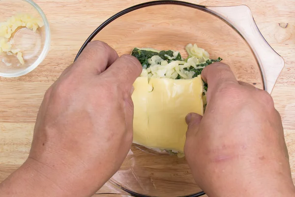 Mettre du fromage dans un bol d'épinards — Photo