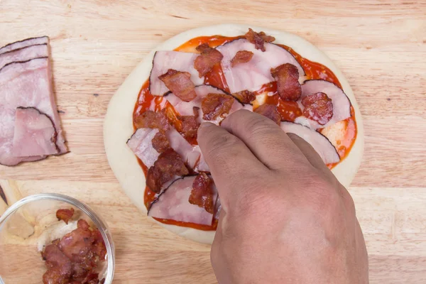 Putting Bacon on pizza crust — Stock Photo, Image