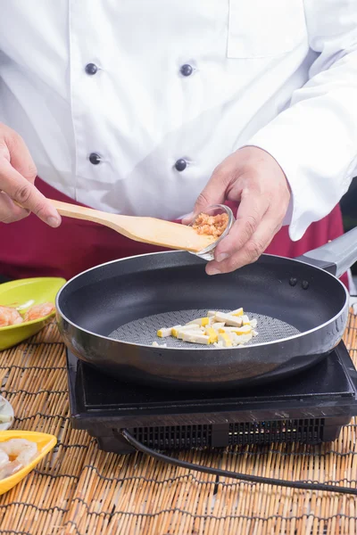 Шеф-повар кладет кусок сушеной редьки на сковородку — стоковое фото