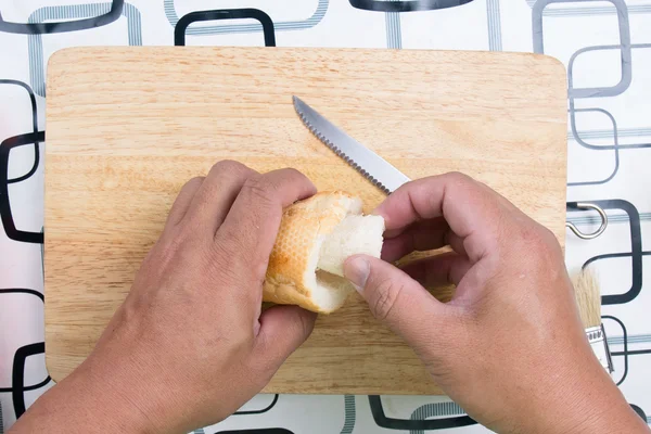 Hand med kniv penetrera bröd — Stockfoto