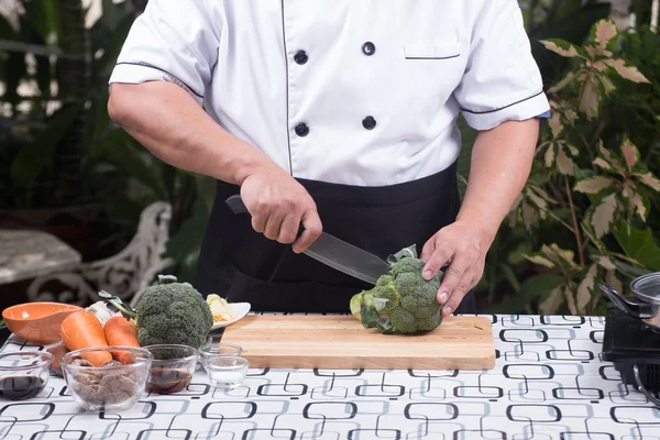 Kocken skär broccoli för matlagning — Stockfoto