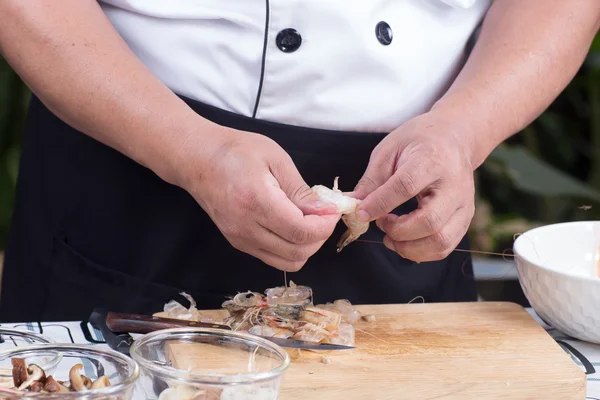 Шеф-повар чистит креветки перед готовкой — стоковое фото