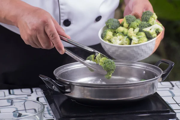 Chef putting broccoli hot water with tongs — Stock Photo, Image