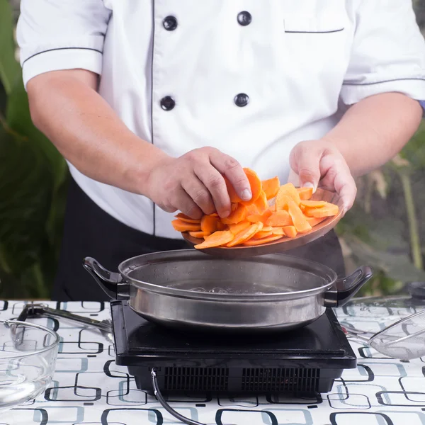 Chef colocando cenoura para cozinhar — Fotografia de Stock