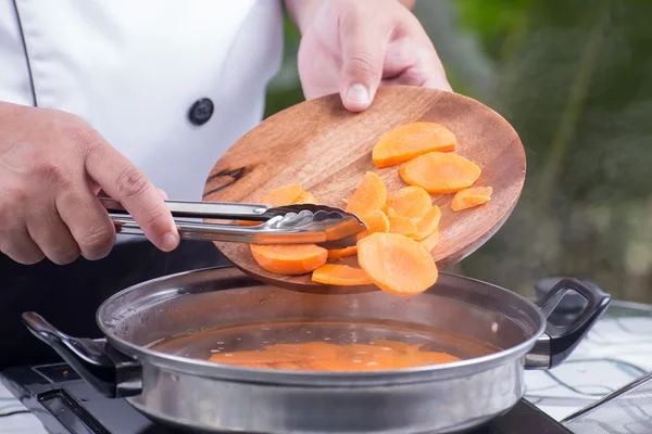 Chef putting carrot for cooking — Stock Photo, Image