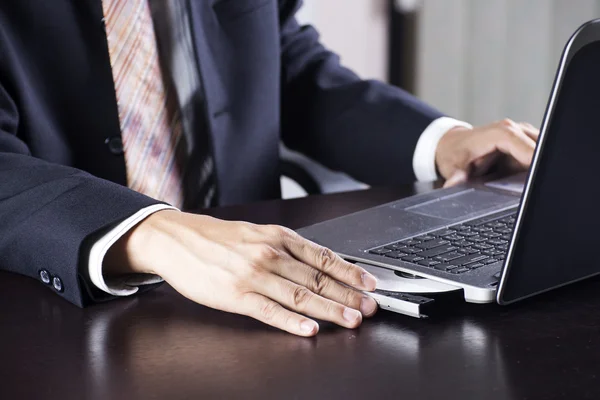 Business man holding Disk insert to laptop — Stock Photo, Image