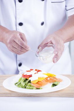 Şef salata sosu koyarak