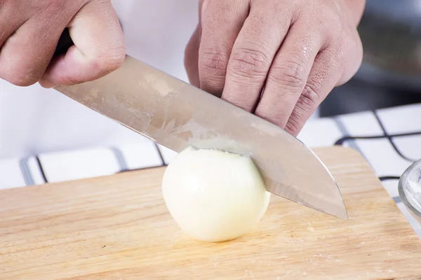Chef cutting the onion on a wooden board — Stock Photo, Image