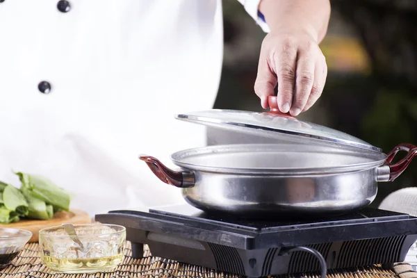 Szef kuchni otwiera pokrywę garnka przed gotowaniem makaronu — Zdjęcie stockowe