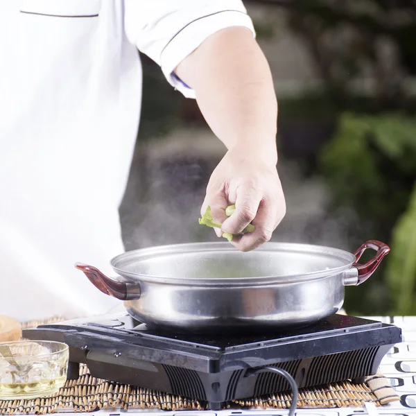 Koch legt Gemüse in Topf, bevor er Nudeln kocht — Stockfoto