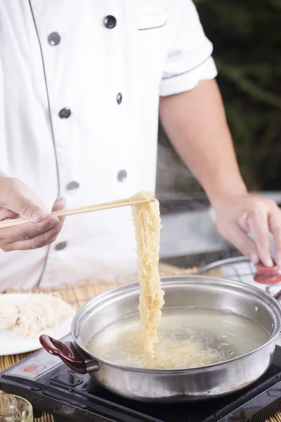 Chef holding the noodle from the pot with chopsticks — Stock Photo, Image