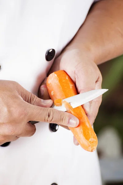 Chef is peeling carrots — Stock Photo, Image