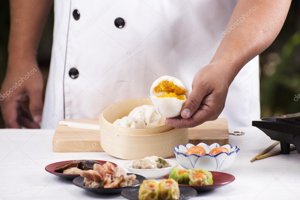 Hand of chefd holding steamed dumpling bun