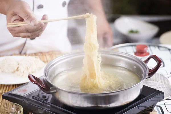 Chef segurando o macarrão do pote com pauzinhos — Fotografia de Stock