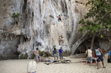Rock climbers climbing the wall on Phra Nang beach clipart